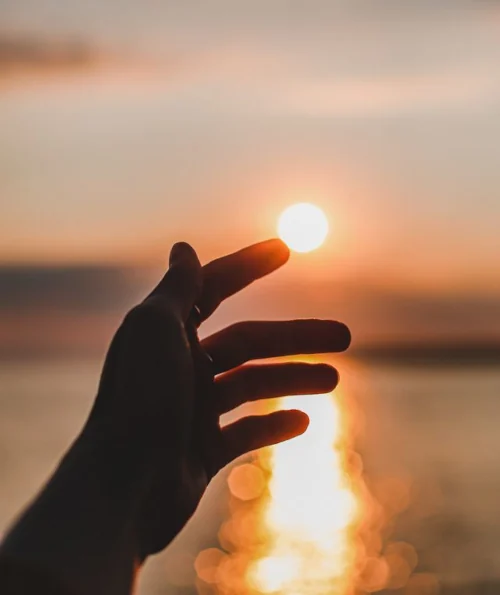 eine Hand die Sonne berührt